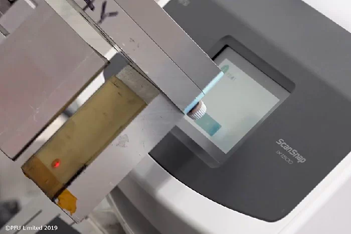 ロボットの先端に付いている指がスキャナーのタッチパネルを押す様子