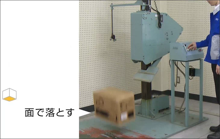 落下試験機の専用テーブルから、梱包物を面で落下させる様子
