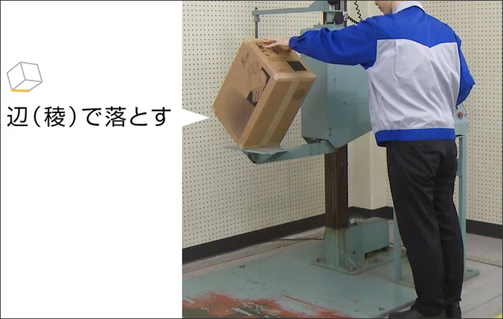 落下試験機の専用テーブルから、梱包物を辺（稜）で落下させる様子