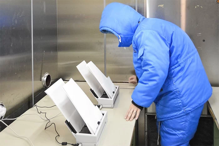 低温試験の環境で防寒具に身を包み、スキャナーの読み取りを確認する様子